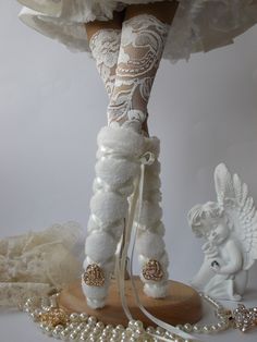 the doll is dressed in white and has her legs covered with lace, pearls and beads