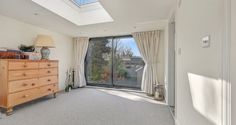 an empty bedroom with a large window and dresser