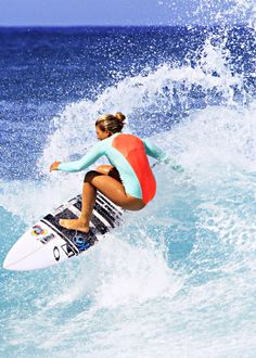 a woman riding a surfboard on top of a wave in the ocean with blue water