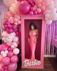 a barbie doll in a pink box surrounded by balloons