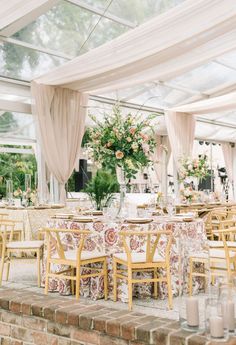 tables and chairs are set up in a tent for an outdoor wedding reception with floral centerpieces