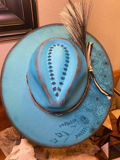 This gorgeous, boho style, turquoise, wide flat brim, fedora crown rancher hat is lightly distressed with hand burned florals, and a custom band with conchos and turkey feathers. Size is adjustable. Made of vegan felt. Unique Hat Bands For Rodeo And Kentucky Derby, Turquoise Hat For Kentucky Derby Festival, Turquoise Bohemian Hat For Country Events, Bohemian Turquoise Hat For Country Events, Turquoise Hat For Kentucky Derby And Country Events, Turquoise Western Fedora With Short Brim, Turquoise Curved Brim Hat For Country Events, Turquoise Bohemian Hat For Kentucky Derby, Turquoise Bohemian Fedora With Short Brim