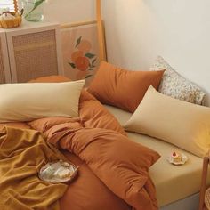 an unmade bed with orange sheets and pillows