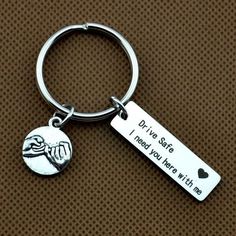 a silver keychain with a hand holding a heart and the words drive safe, i need you here with me