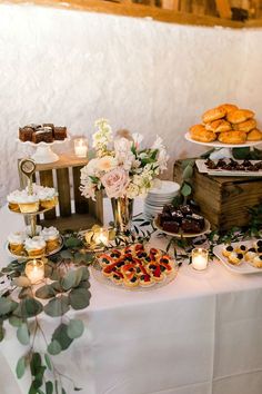 a table filled with desserts and pastries on top of a white table cloth