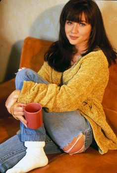 a woman sitting on a couch holding a cup