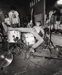 a man laying on top of a drum kit in front of a group of people