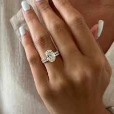 a woman's hand with a ring on it and a white manicured nail polish