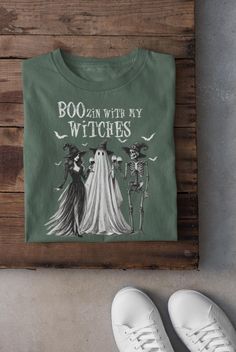 This Comfort Colors Halloween Party T-Shirt is perfect for women who love Halloween festivities and want to show off their festive spirit. The design features a ghost, skeleton, and witch drinking wine together, making it a fun and quirky shirt for Halloween parties. It's a great gift idea for her and is ideal for those who enjoy 'Boozin with my witches'. The relaxed fit and high-quality cotton fabric make it comfortable to wear for casual or semi-formal occasions. Product features - Available i Witch Tshirt Ideas, Cotton Tops With Letter Print For Costume Party, Crew Neck Graphic Print T-shirt For Costume Party, Graphic Print Crew Neck T-shirt For Costume Party, Green Halloween T-shirt With Character Print, Fall Crew Neck T-shirt For Costume Party, Crew Neck Tops With Letter Print For Costume Party, Graphic Print Crew Neck Shirt For Costume Party, Spooky Letter Print T-shirt For Costume Party