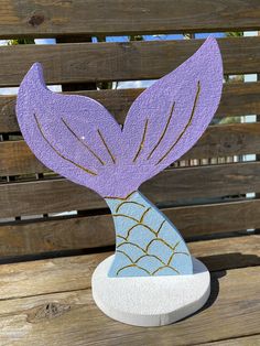 a paper cut out of a mermaid tail sitting on top of a wooden bench