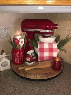 a red mixer sitting on top of a counter next to other kitchen accessories and utensils