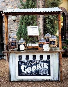 an old fashioned ice cream stand is decorated with pine trees and jars for sale in front of a brick building