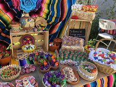 a table filled with lots of food and desserts next to a rainbow colored blanket