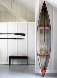 an old canoe is hanging on the wall in a room with white walls and flooring