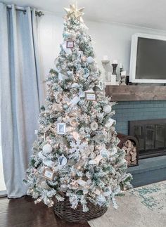 a decorated christmas tree in a living room with white and silver decorations on the top