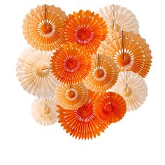 several orange and white paper fans hanging from the ceiling in front of a white background