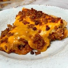 a white plate topped with a cheesy casserole covered in cheese and meat