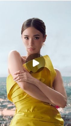 a woman in a yellow dress is posing for a photo with the city behind her