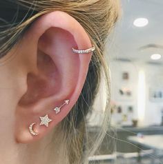 a woman wearing an ear piercing with stars and moon designs on it's side