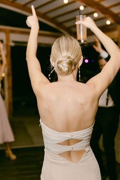 the back of a woman's dress as she holds her arms in the air