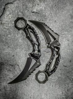 two black knives sitting next to each other on top of a stone surface with one knife stuck in it's blade