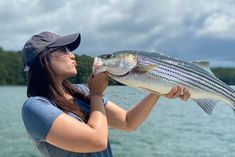 a woman holding up a fish while standing on a boat