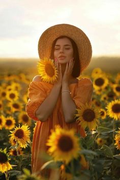 a woman standing in a field of sunflowers holding her hands to her face