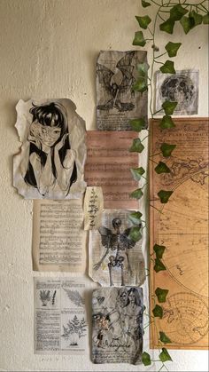 various papers and pictures are hanging on the wall next to a plant with ivy growing in it