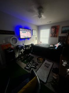 a room with a bed, desk and television in it at night time that is lit up by blue lights