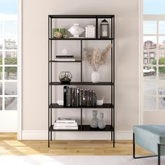 a black shelf with books and vases on it in front of a white wall