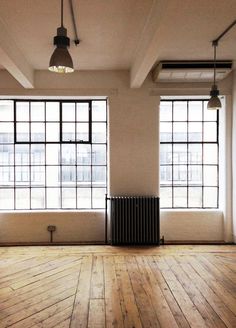 an empty room with large windows and wooden floors