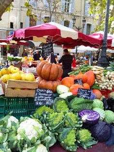 an open air market with lots of fresh vegetables and fruits on the table in front of it