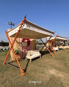 an outdoor tent is decorated with orange ribbons and flowers on the grass in front of it