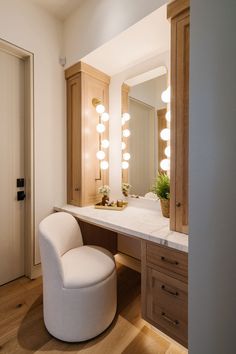 a white chair sitting in front of a mirror on top of a bathroom counter next to a sink