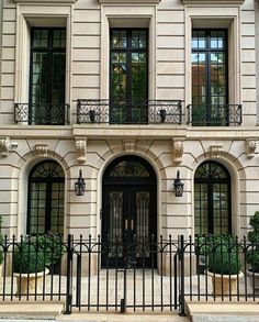 a large white building with black wrought iron doors and windows on the front door is shown