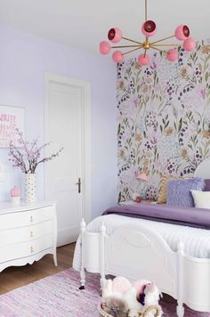 a white bed sitting in a bedroom next to a pink wallpaper covered with flowers