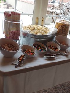 a table topped with lots of different bowls filled with food next to a large window