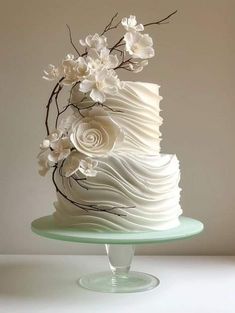 there is a white cake with flowers on the top and bottom, sitting on a glass plate