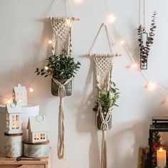 three macrame plant hangers with plants in them and some lights on the wall