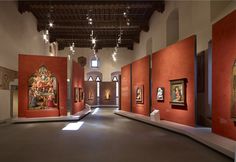 an empty room with paintings on the walls and ceiling lights hanging from the rafters