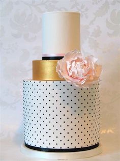 a white and black polka dot cake with a pink flower on top