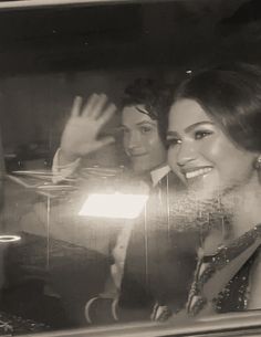 black and white photograph of two women waving out the window at someone in front of them