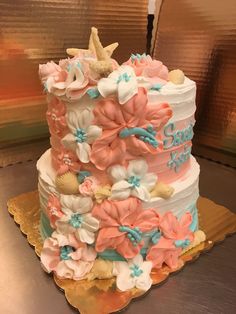 a three tiered cake decorated with flowers and seashells