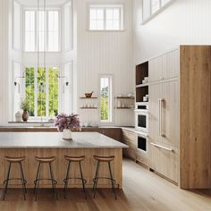 a large kitchen with wooden floors and white walls, has an island in the middle