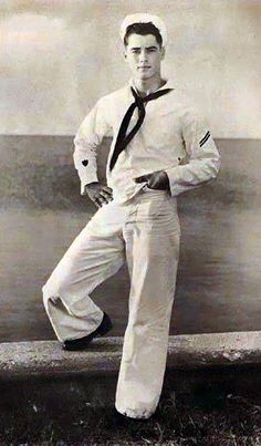 an old black and white photo of a man in sailor's outfit leaning on a wall