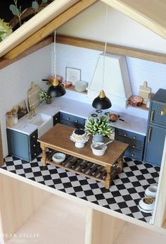 a dollhouse kitchen with black and white checkered flooring, potted plants on the table