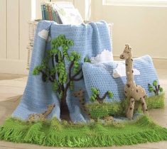 a crocheted blanket with giraffes and trees on it