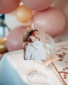 a baby's first birthday card is placed on a table with balloons in the background