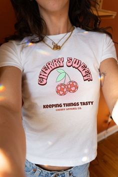 Get ready to step back in time with our Coconut Girl Y2K-inspired fitted BabyTee! This trendy 90's tee features a playful design of two disco ball cherries and the saying "cherry sweet" across the front. Made from a soft blend of 50% cotton and 50% polyester, this cute Y2K tee will keep you stylish all day long. The vibrant print and unique design add a fun, retro touch to any outfit. Perfect for casual outings or lounging at home, this 90's fitted tee is a must-have for those who love Y2K and c Cute Fitted Cropped T-shirt For Streetwear, Trendy Cropped T-shirt With Funny Print And Short Sleeves, Trendy Cropped T-shirt With Funny Print, Fitted Vintage Top With Graphic Design, Retro Fitted Cropped T-shirt With Crew Neck, Fitted Retro Cropped T-shirt Crew Neck, Retro Fitted Crew Neck Cropped T-shirt, Retro Cotton Cropped T-shirt With Short Sleeves, Retro Cropped Cotton T-shirt With Short Sleeves