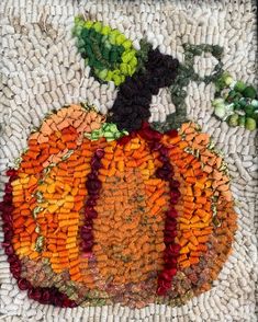 a close up of a pumpkin made out of corn kernels and other things on the ground